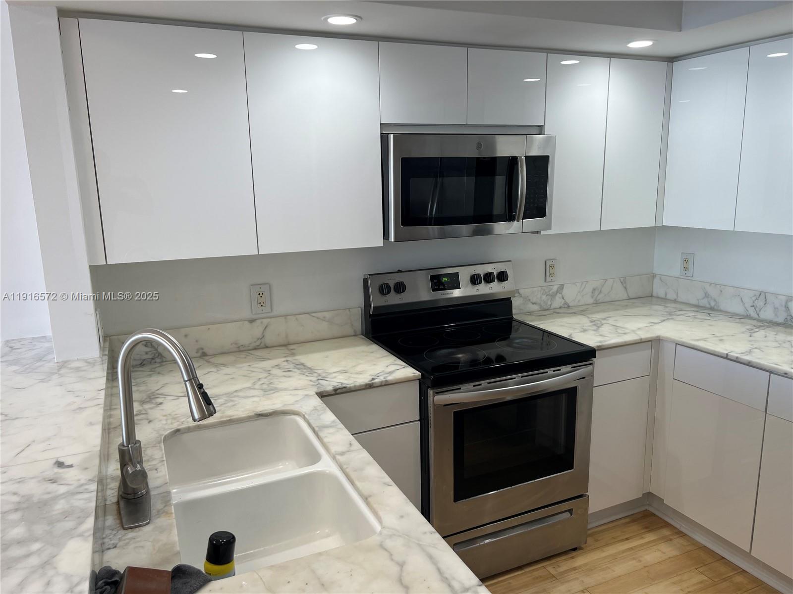 5600 Collins Avenue, Unit 17T Miami Beach, FL 33140 - Photo 16 of 52 a kitchen with a sink stove and microwave