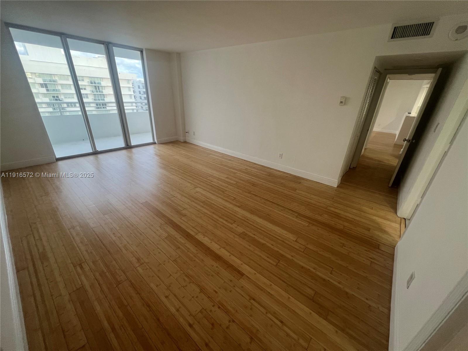 5600 Collins Avenue, Unit 17T Miami Beach, FL 33140 - Photo 23 of 52 a view of an empty room with wooden floor and a window