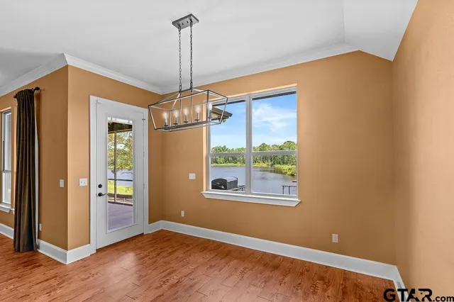 a view of an empty room with window and wooden floor