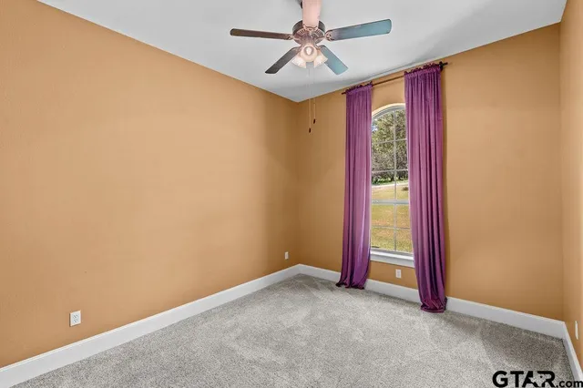 an empty room with floor to ceiling window and ceiling fan