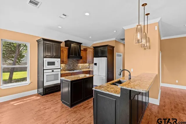 a kitchen with stainless steel appliances granite countertop a refrigerator and a stove top oven