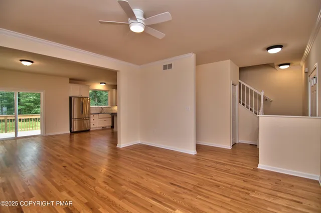 a view of empty room with wooden floor and fan