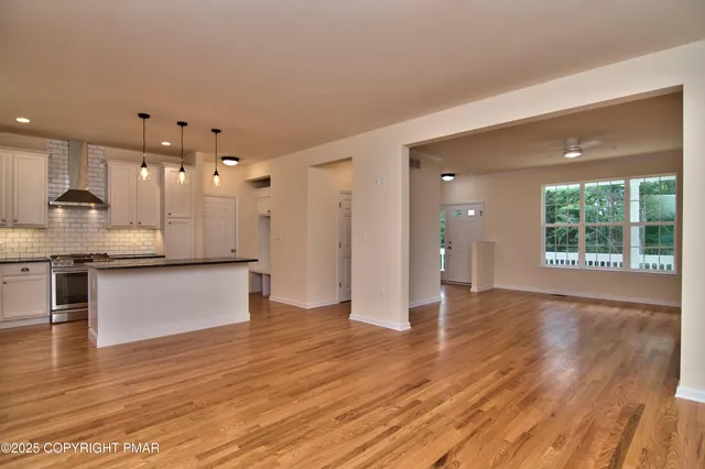 a view of kitchen with kitchen island wooden floor center island and stainless steel appliances