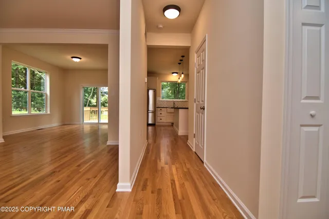 a view of a hallway with wooden floor and a living room