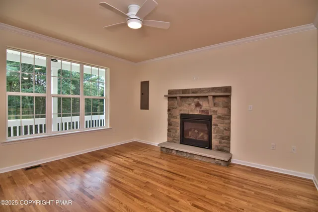 a view of an empty room with wooden floor fireplace and a window