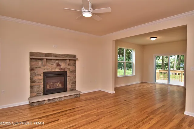 a view of an empty room with wooden floor fireplace and a window