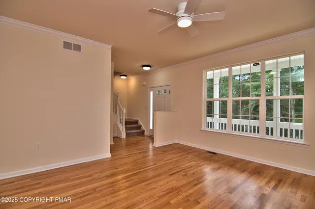 a view of an empty room with a window and wooden floor
