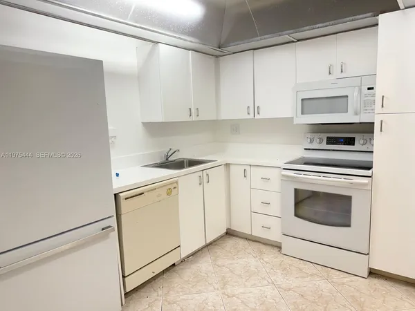a kitchen with white cabinets and white appliances