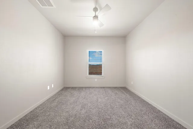 an empty room with a window and a ceiling fan