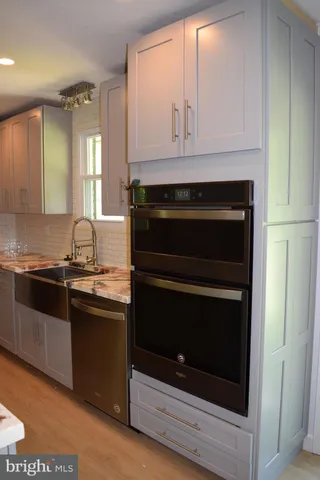 a kitchen with granite countertop white cabinets and appliances