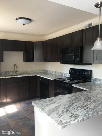 a kitchen with granite countertop a stove a sink and a microwave