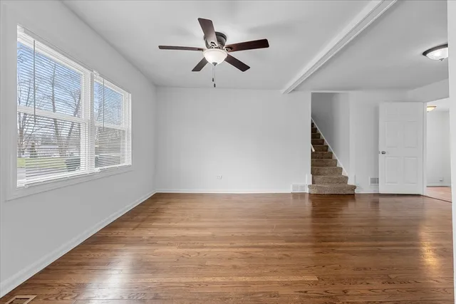a view of empty room with wooden floor and ceiling fan
