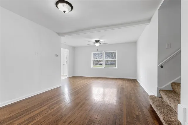 an empty room with wooden floor cabinet and windows