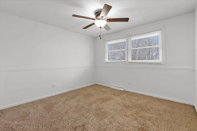 an empty room with a chandelier fan and windows