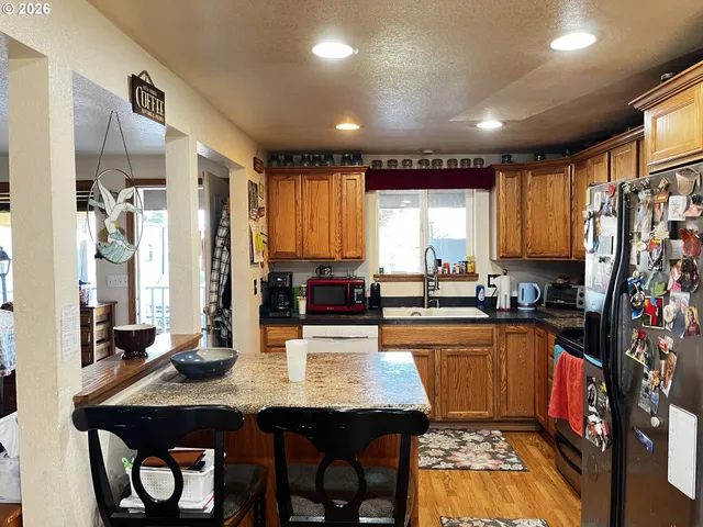 a kitchen with stainless steel appliances a dining table chairs refrigerator and sink