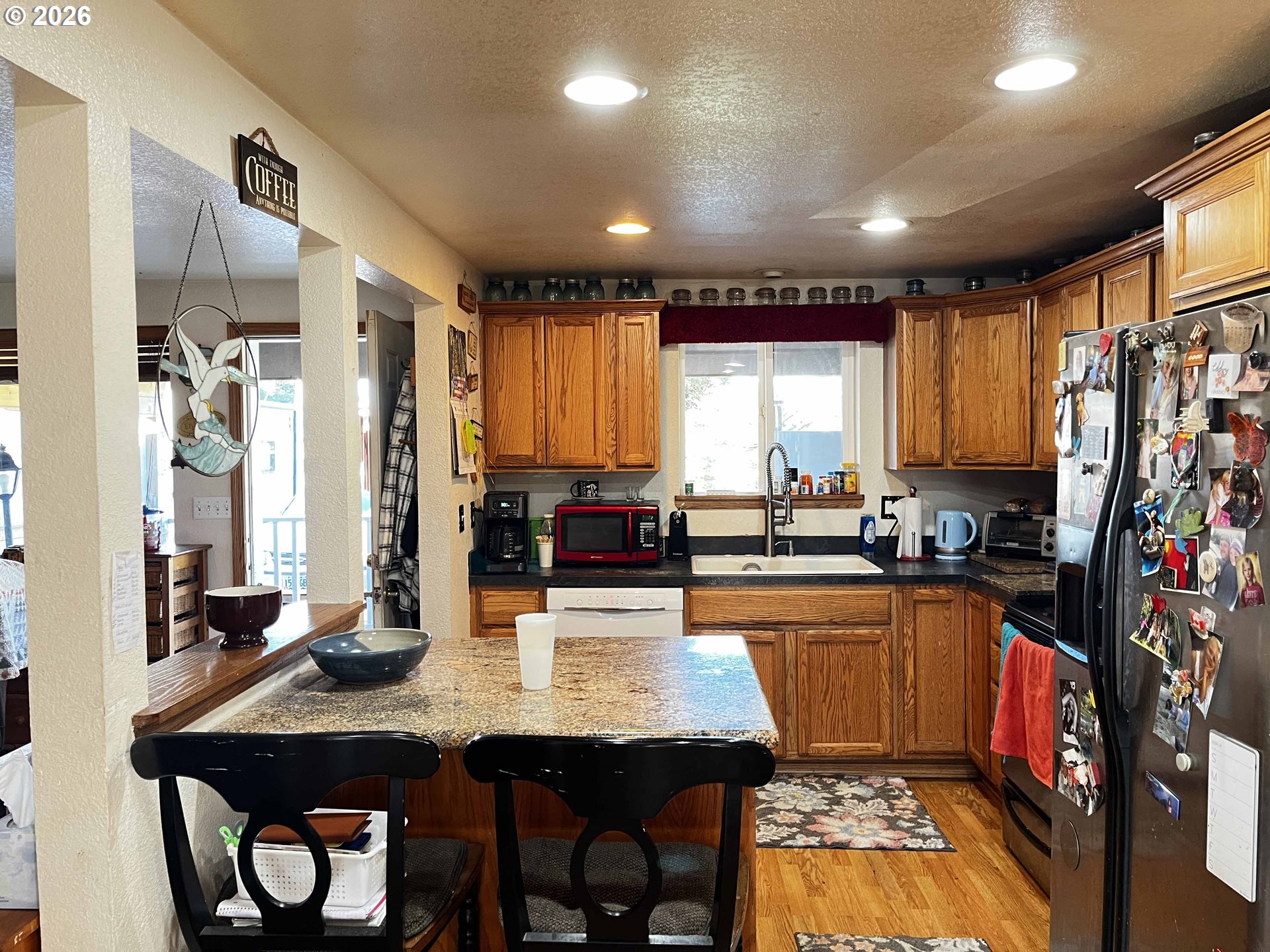 1890 37th Street Florence, OR 97439 - Photo 12 of 41 a kitchen with stainless steel appliances a dining table chairs refrigerator and sink
