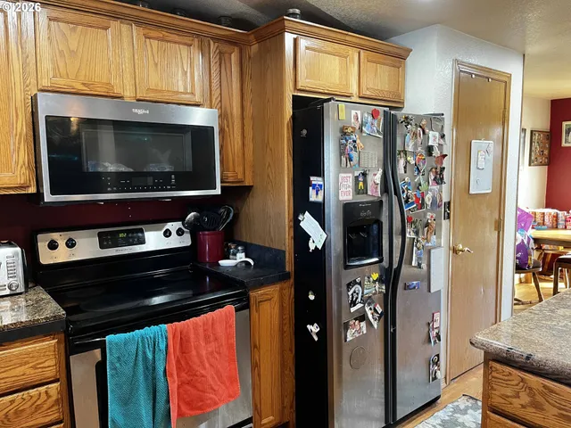a living room with stainless steel appliances furniture a fireplace and a flat screen tv