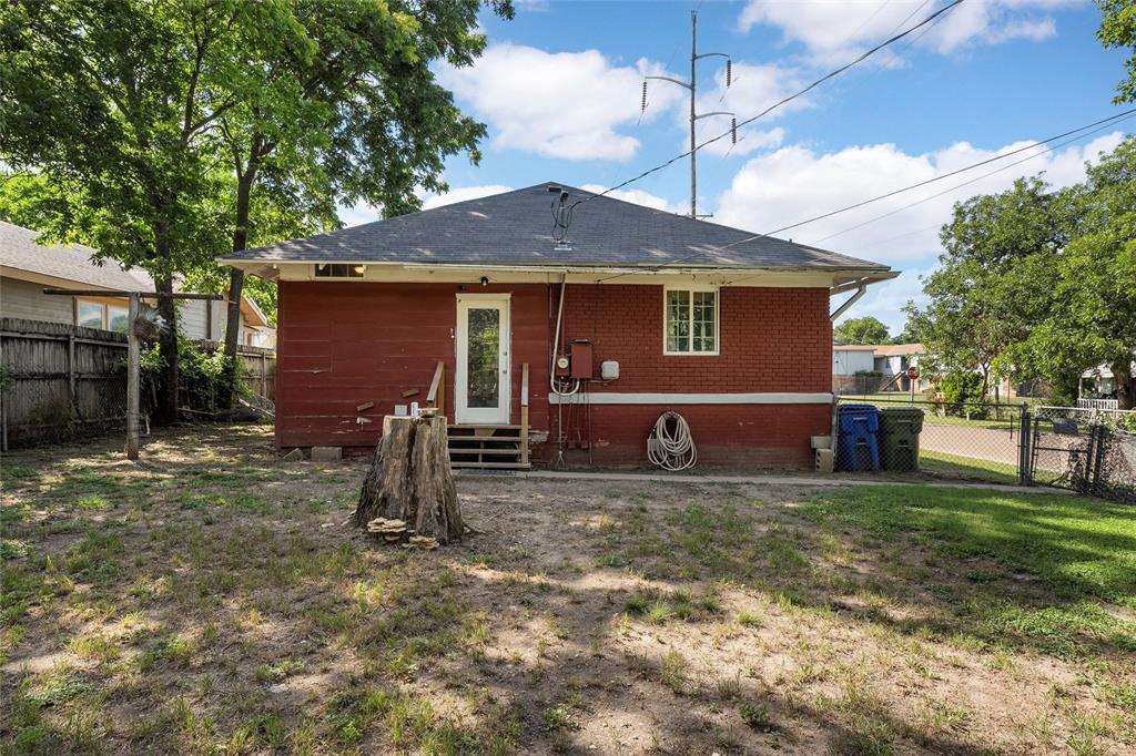 2700 Cole Avenue Waco, TX 76707 - Photo 13 of 14 Back of property with entry steps, a fenced backyard, brick siding, roof with shingles, and a gate