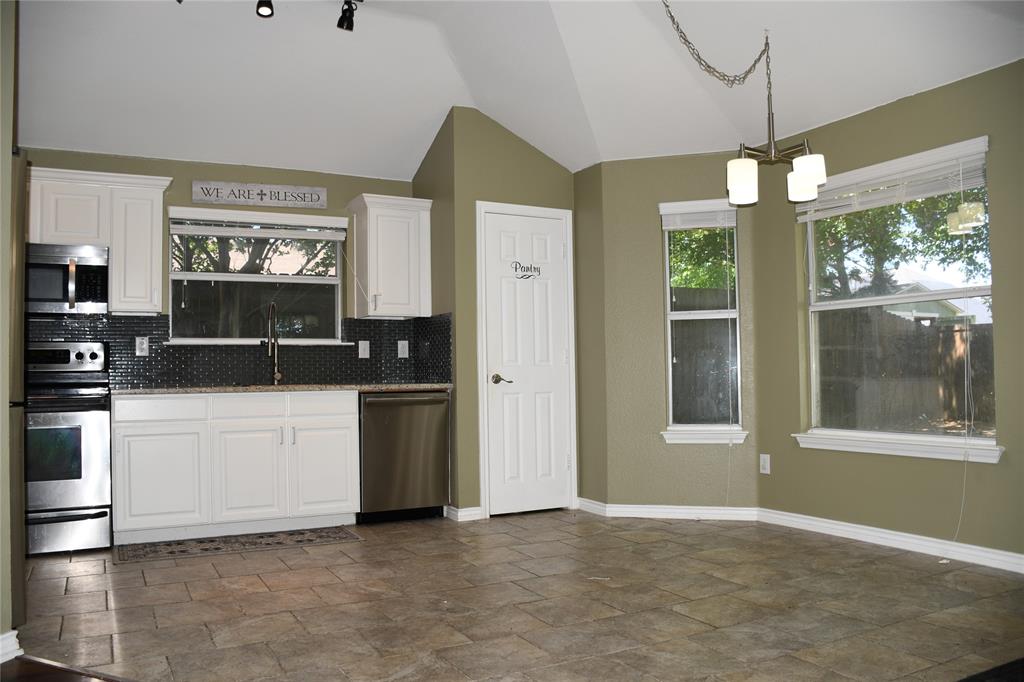 6241 Peach Tree Drive Midlothian, TX 76065 - Photo 5 of 19 Kitchen area featuring white cabinetry, stainless steel appliances, dark tile backsplash, and a vaulted ceiling