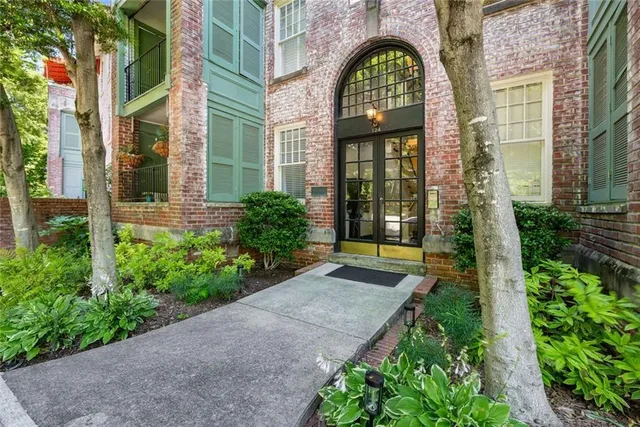 a view of a brick house with a large windows and flower plants