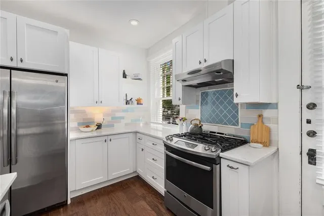 a kitchen with stainless steel appliances granite countertop a stove a refrigerator and a white cabinets