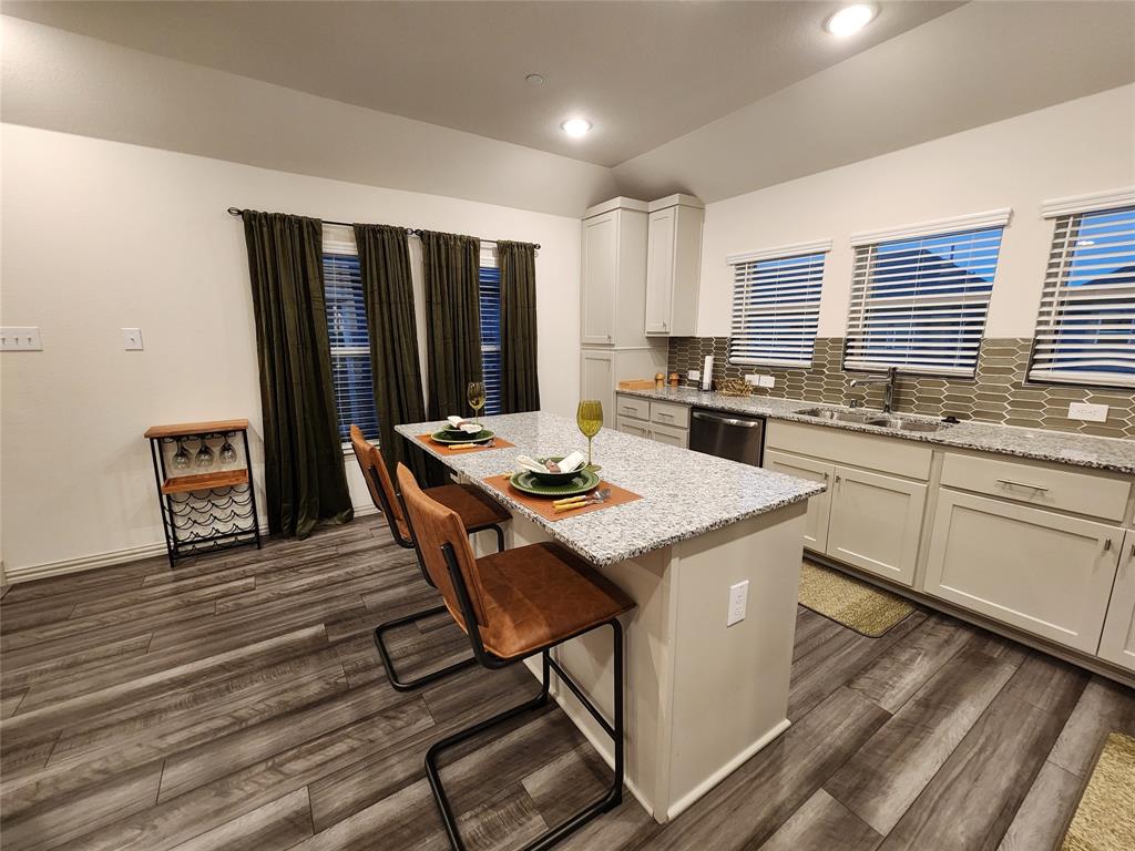 4708 Haltom Road Haltom City, TX 76117 - Photo 13 of 29 a kitchen with a stove a sink dishwasher a kitchen island with chairs and wooden floor