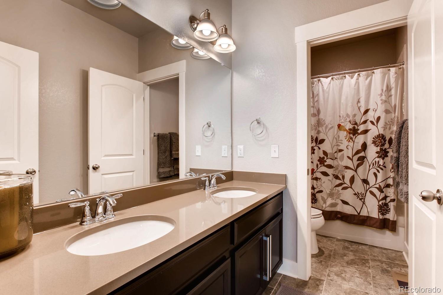 2858 Lima Street Denver, CO 80238 - Photo 19 of 28 a bathroom with a granite countertop sink a light fixture and a mirror