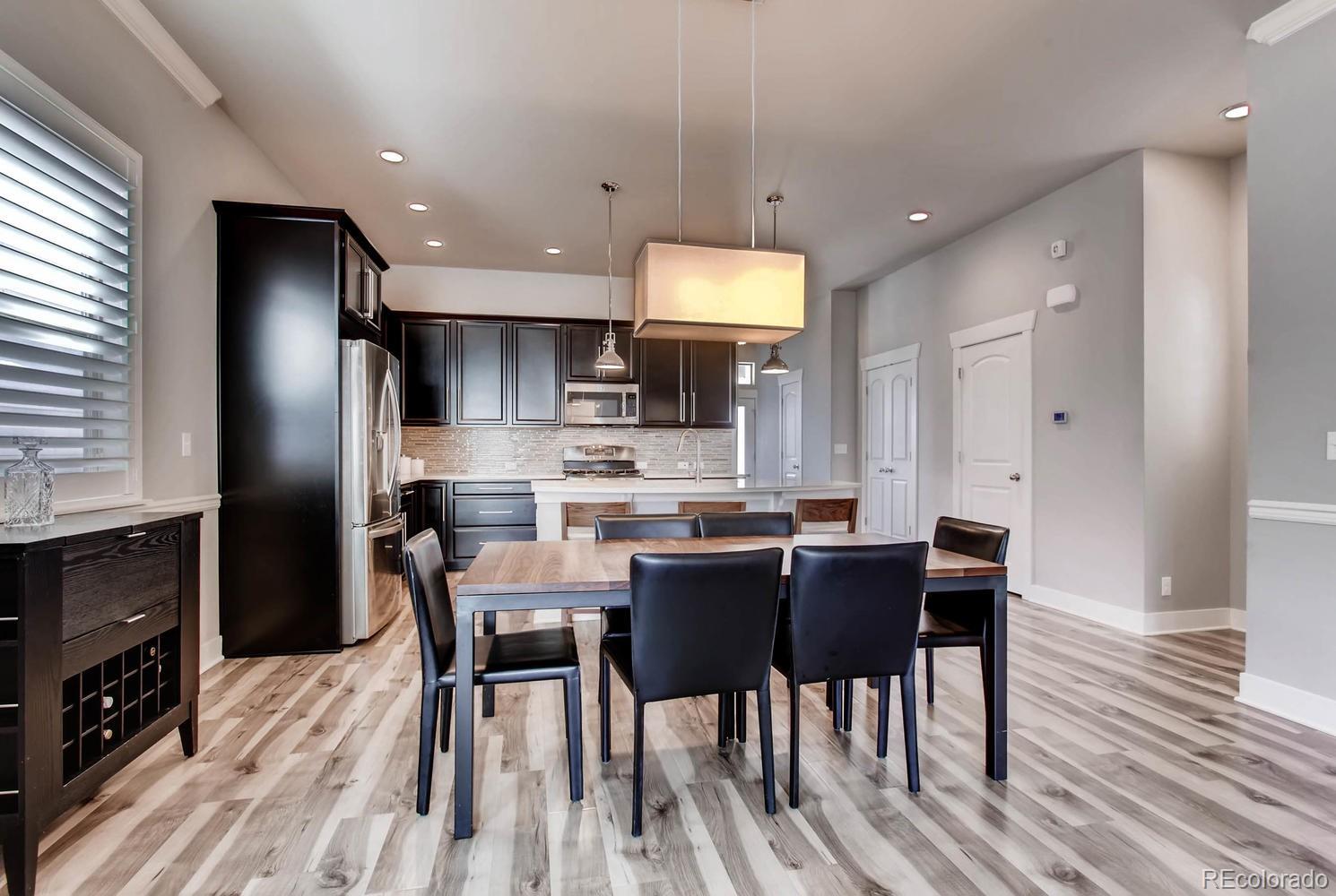 2858 Lima Street Denver, CO 80238 - Photo 7 of 28 a kitchen with stainless steel appliances a dining table chairs stove refrigerator and cabinets