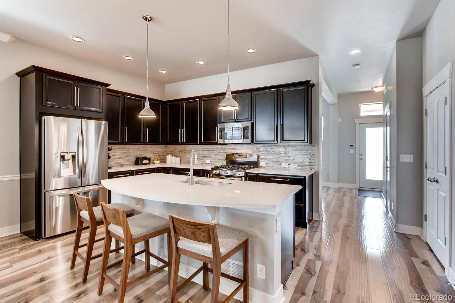 2858 Lima Street Denver, CO 80238 - Photo 10 of 28 a kitchen with stainless steel appliances kitchen island granite countertop a refrigerator a stove a sink a dining table and chairs with wooden floor