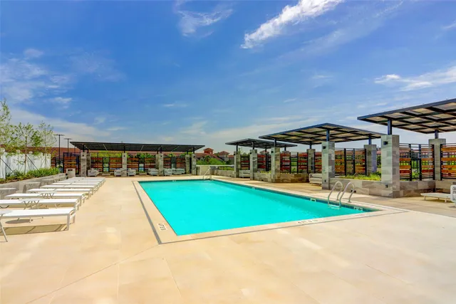 a view of pool with lawn chairs under an umbrella