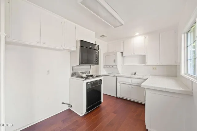 a kitchen with a sink cabinets stainless steel appliances and a window
