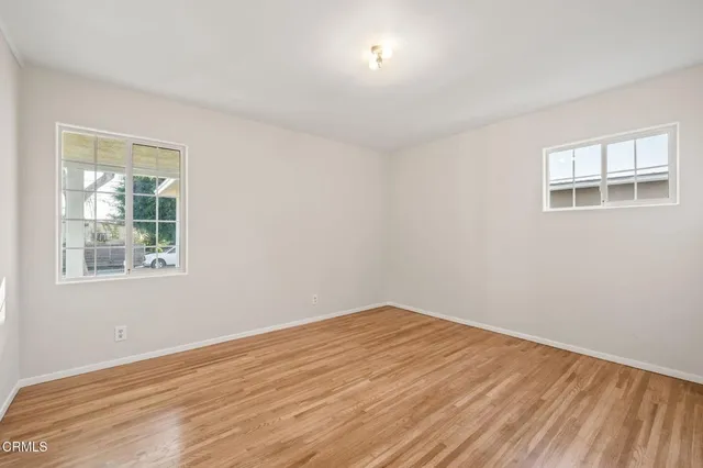 a view of empty room with wooden floor and fan