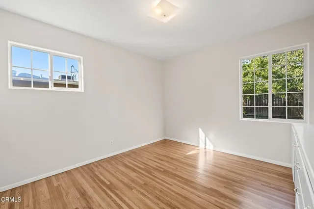 a view of empty room with wooden floor and fan