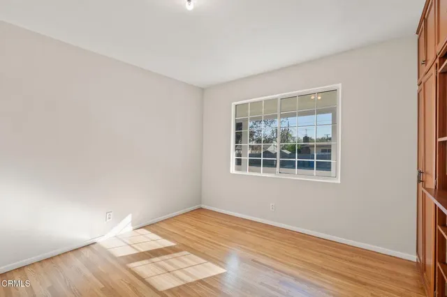 a view of an empty room with wooden floor and a window