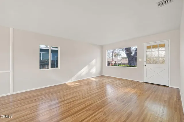 a view of an empty room with wooden floor and a window