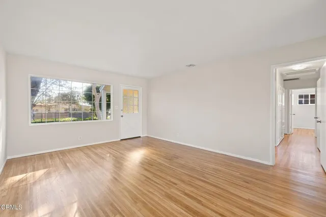 a view of an empty room with wooden floor and a window