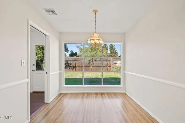 a view of a room with wooden floor chandeliers and kitchen view