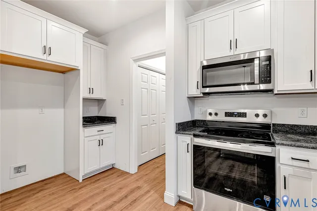 a kitchen with cabinets stainless steel appliances and wooden floor