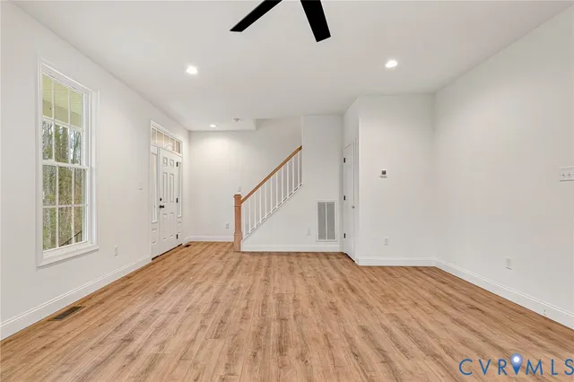a view of empty room with wooden floor and fan
