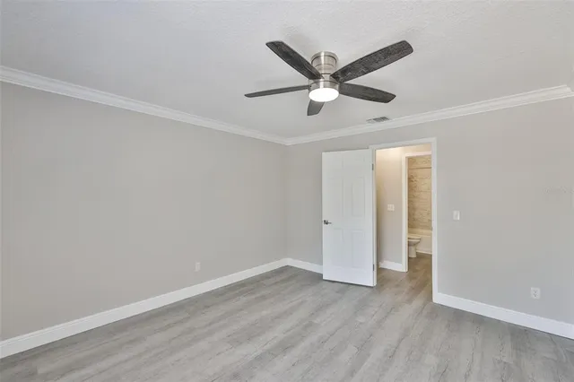 an empty room with wooden floor ceiling fan and window