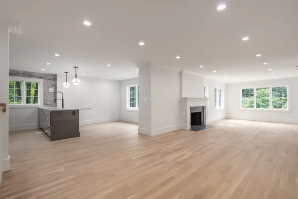 a view of an empty room with wooden floor and a kitchen