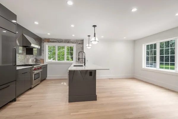 a kitchen with stainless steel appliances granite countertop a sink a stove and a wooden floors