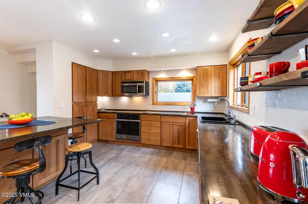 a kitchen with stainless steel appliances a stove a sink a refrigerator cabinets and wooden floor