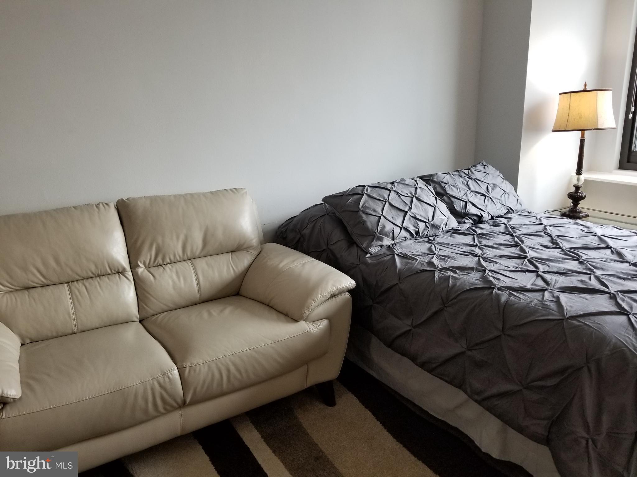 1021 Arlington Boulevard, Unit 414 Arlington, VA 22209 - Photo 7 of 31 a bedroom with a bed and a couch