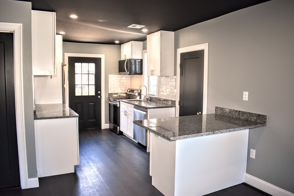 2 Sunnyside Street, Unit 2 Boston, MA 02130 - Photo 2 of 41 a kitchen with stainless steel appliances granite countertop a refrigerator a stove a sink and white cabinets with wooden floor
