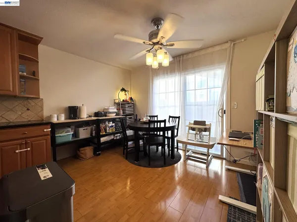 a dining room with wooden floor a chandelier fan a wooden table and chairs