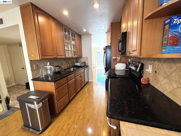 a kitchen with granite countertop stove top oven microwave and cabinets