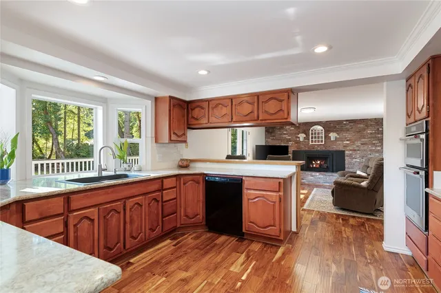 a kitchen with stainless steel appliances granite countertop a stove a sink dishwasher and a microwave oven with wooden floor