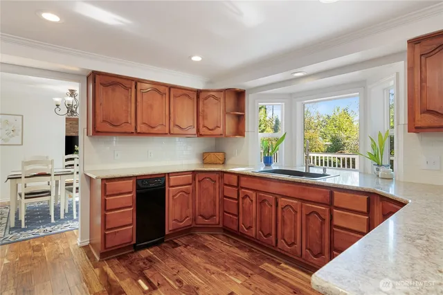 a kitchen with stainless steel appliances granite countertop wooden cabinets a sink and dishwasher a stove with wooden floor