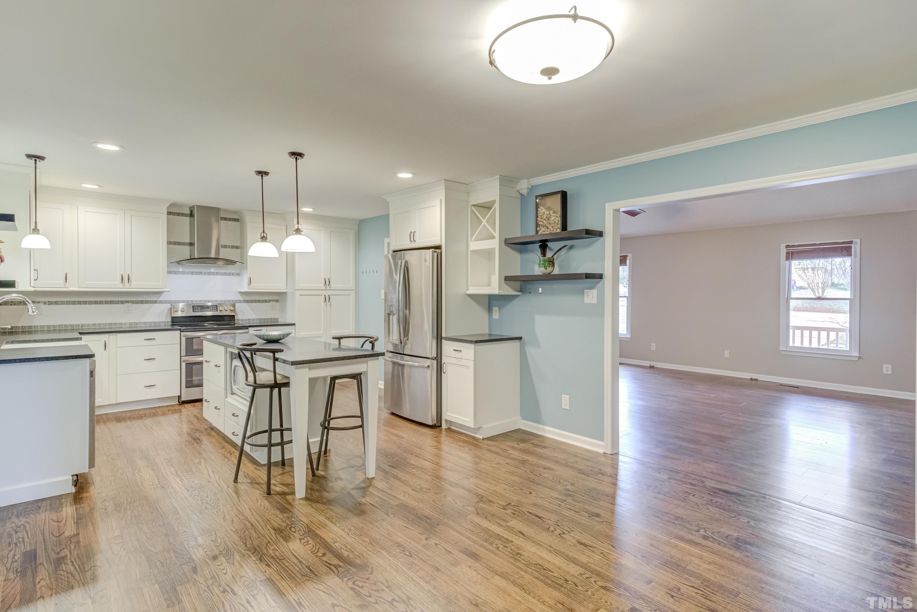 605 Jordan Ridge Lane Raleigh, NC 27603 - Photo 7 of 36 a kitchen with stainless steel appliances kitchen island granite countertop a refrigerator a stove a sink and white cabinets with wooden floor
